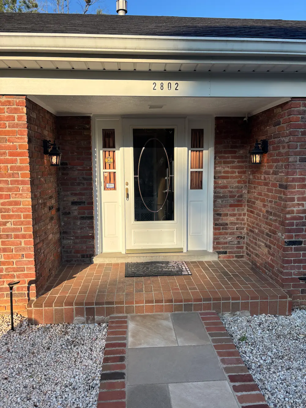 Original white entry door with sheer curtains at sidelites before replacement
