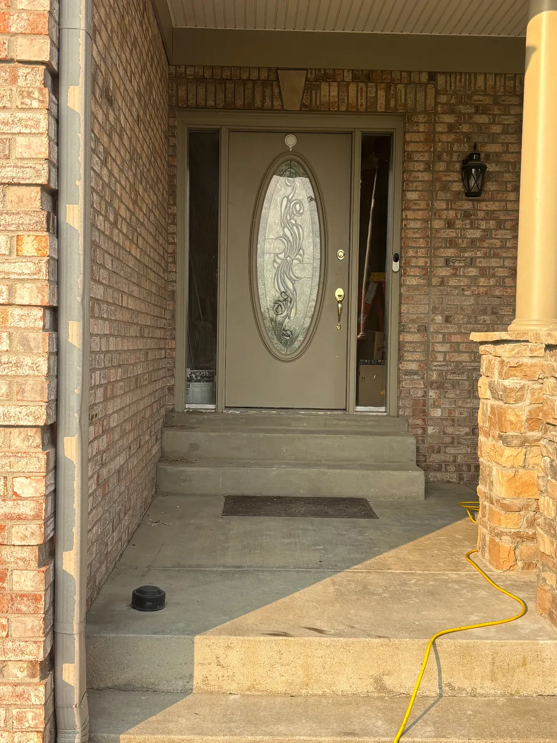 Original single taupe entry door with oval glass insert before replacement